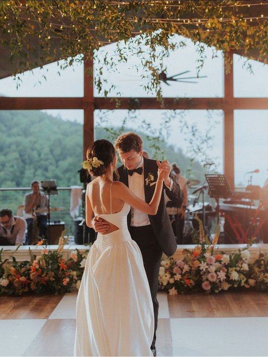 Bride and groom dancing under romantic string lights with a Smoky Mountain backdrop